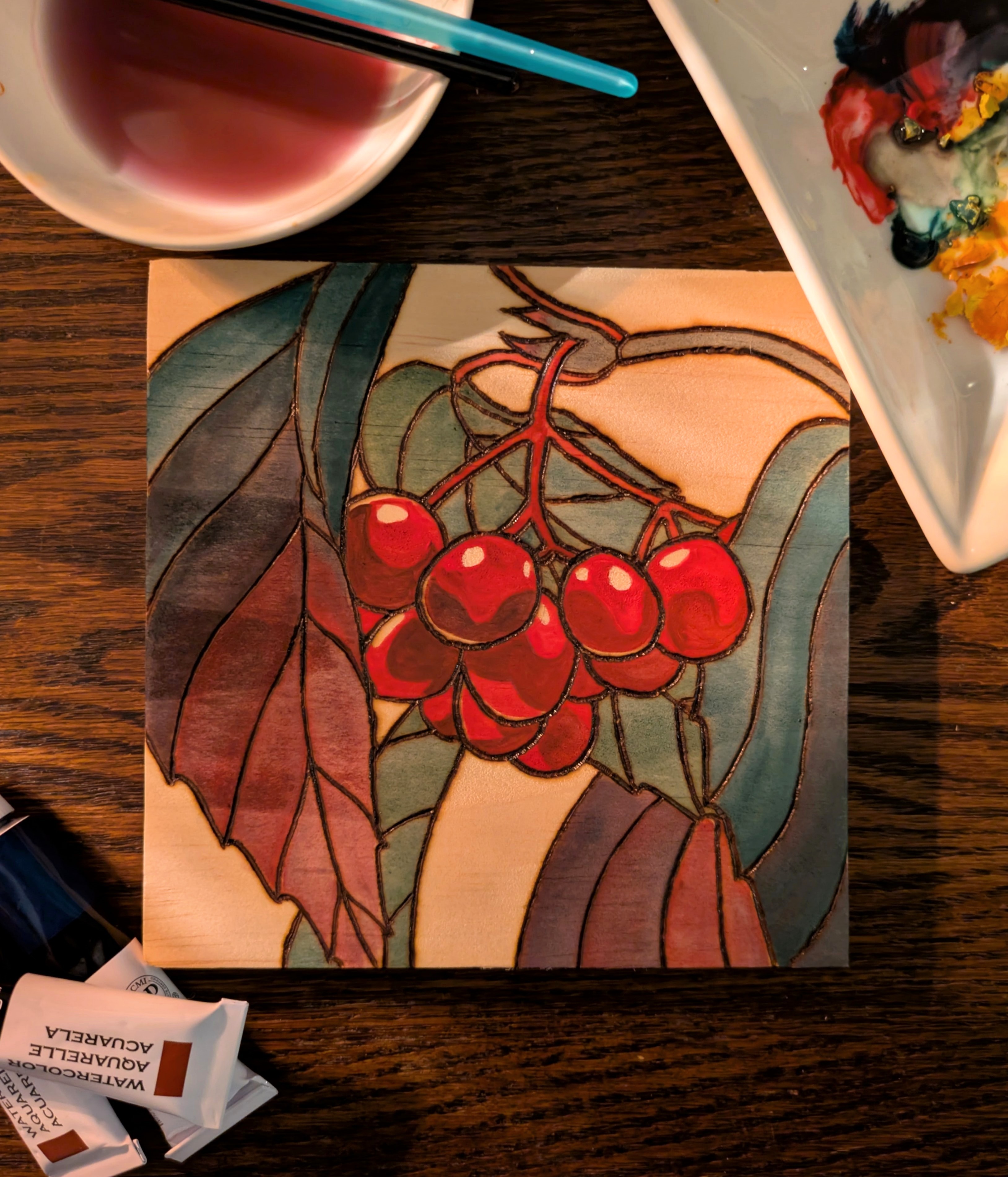 Pyrography and watercolor of bright red berries and stylized blue through red leaves