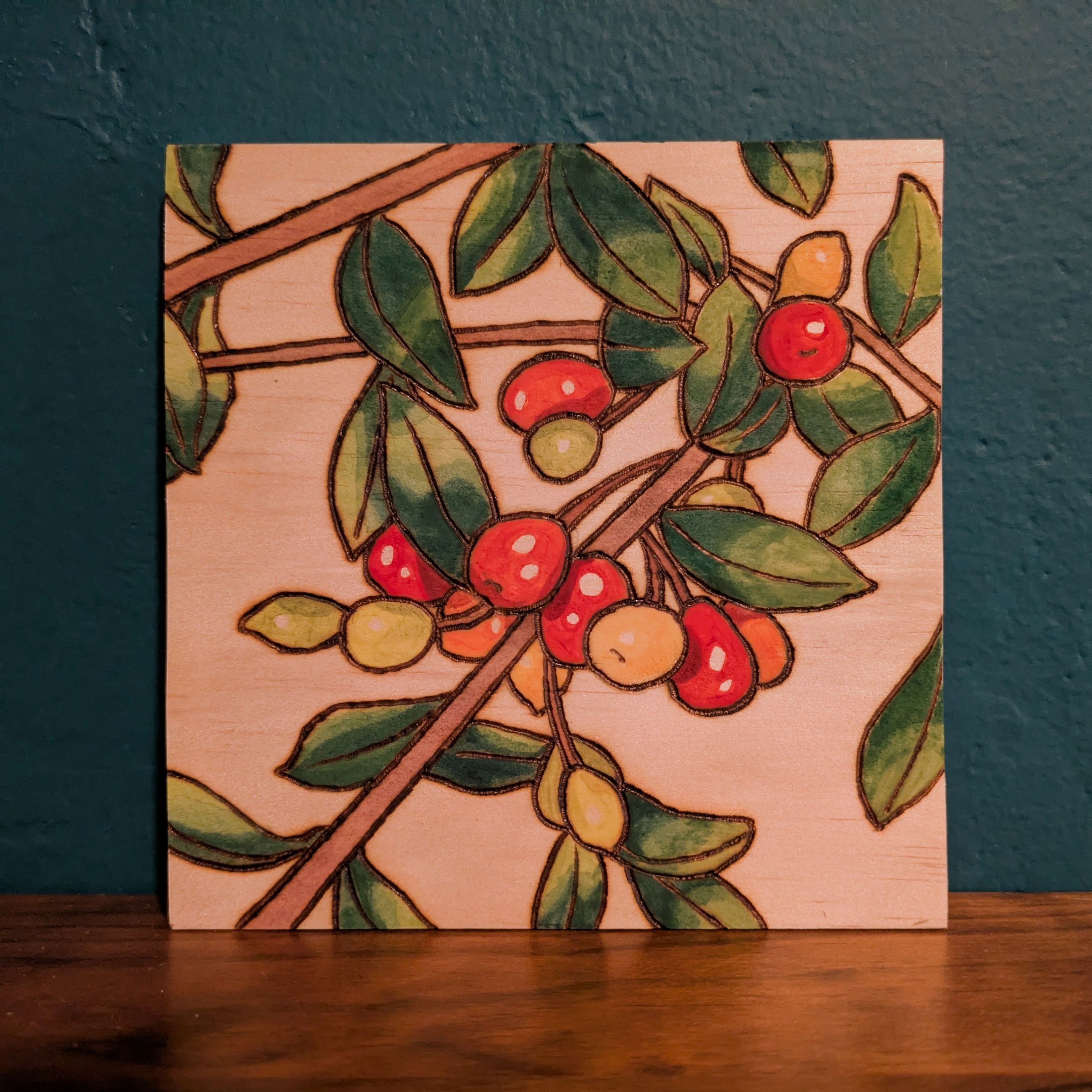 Pyrography and watercolor of Red, organge, and yellow berries on a branch